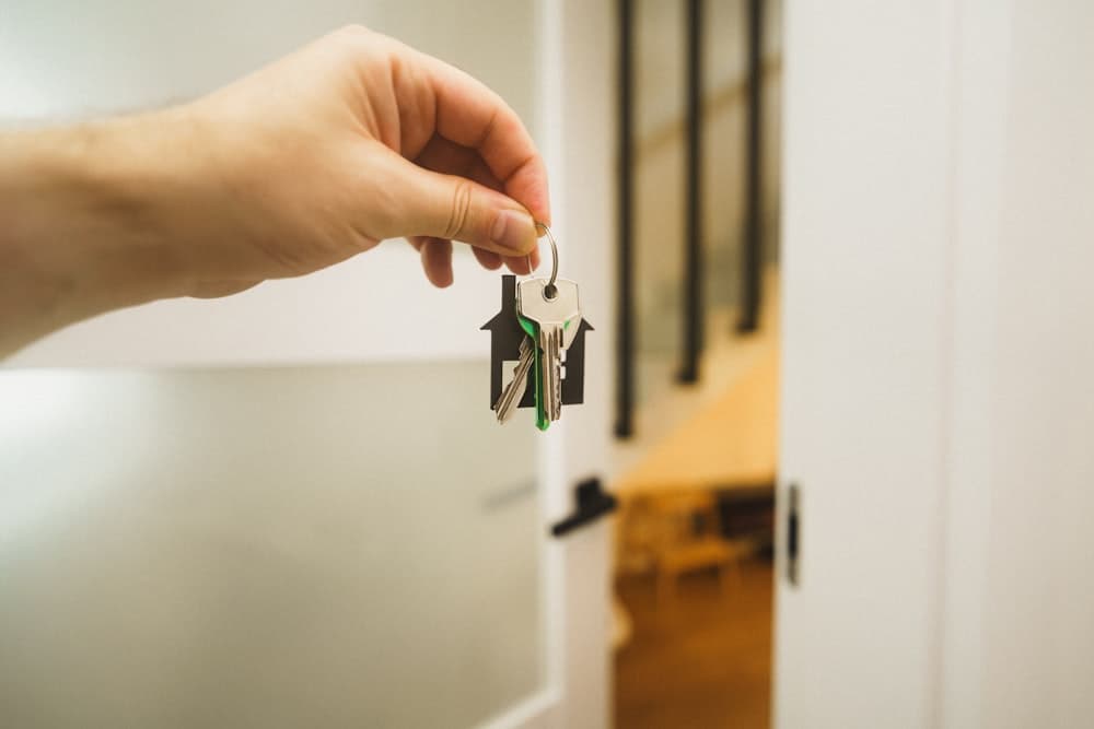 A hand holding a set of house keys in a doorway